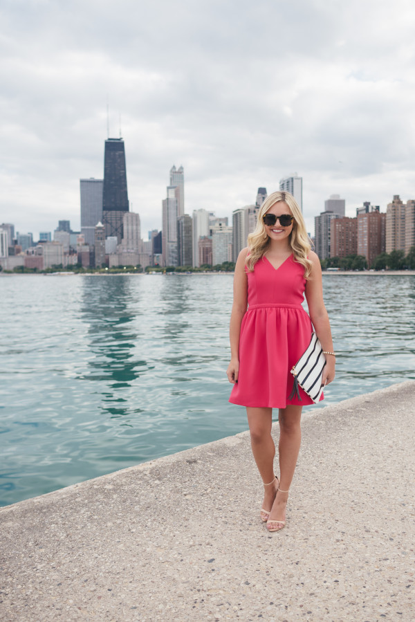 pink dress, navy striped clutch, chicago skyline along the lake hancock building