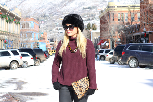 Fashion blogger wearing a faux fur hat, Valentino rockstud sunglasses, chunky turtleneck sweater, and Clare V Leopard Clutch in Aspen.