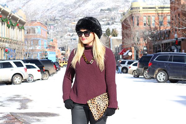 Fashion blogger wearing a faux fur hat, Valentino rockstud sunglasses, chunky turtleneck sweater, and Clare V Leopard Clutch in Aspen.