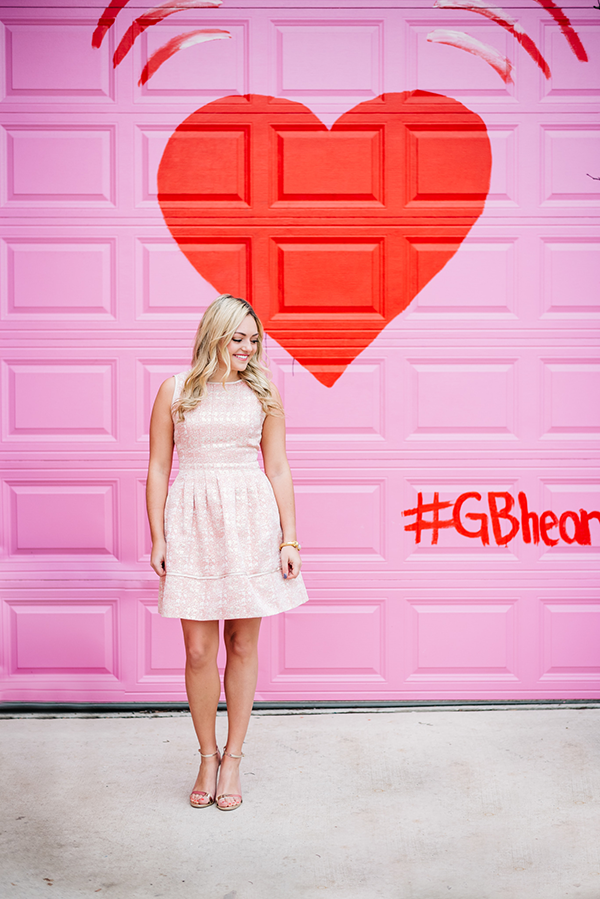 Bows & Sequins styling a light pink dress in front of a pink and red heart wall in Chicago.
