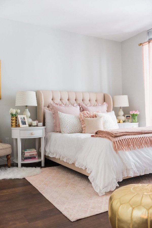 Blogger Jessica Sturdy of Bows & Sequins shares her Chicago Parisian-chic bedroom design. Tufted linen headboard, blush pink rug, and white, ruffled bedding.