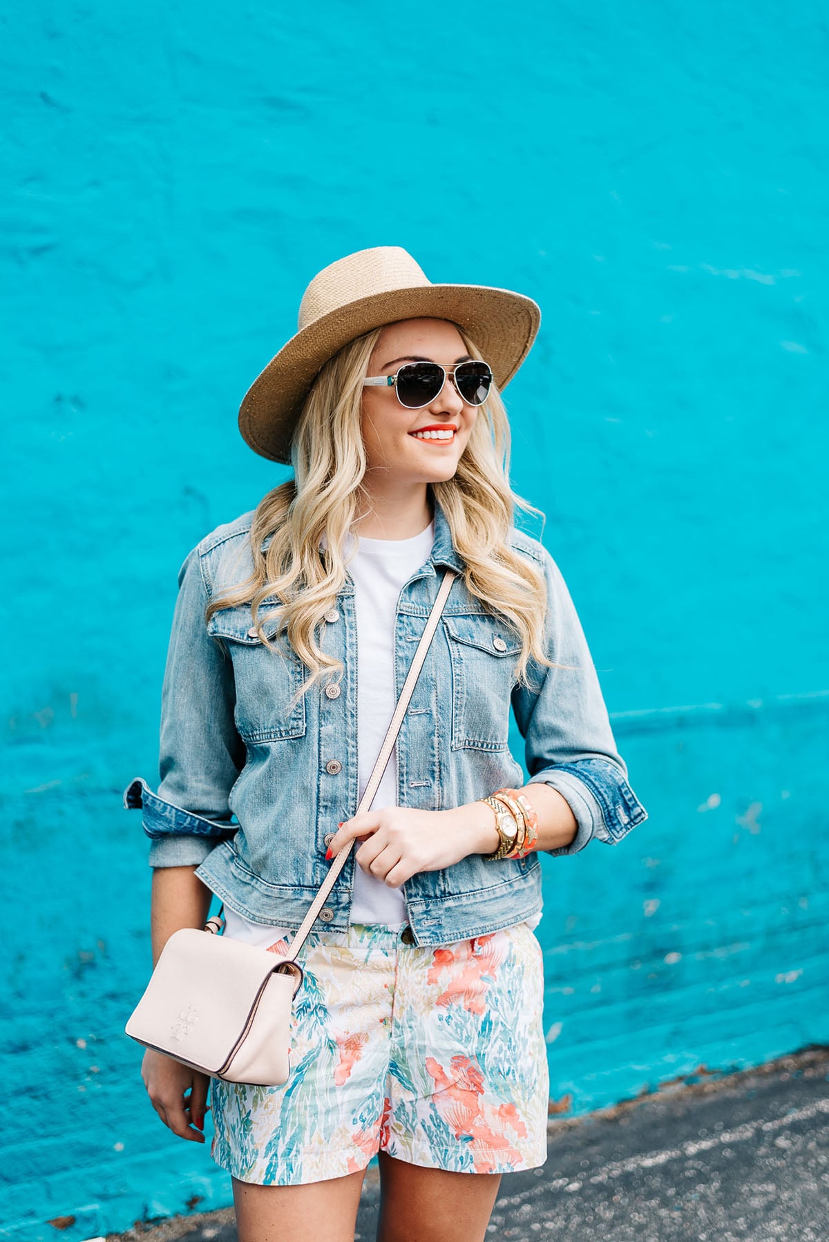 colorful summer outfit, wide brim straw hat, denim jacket, printed shorts, white aviator sunglasses