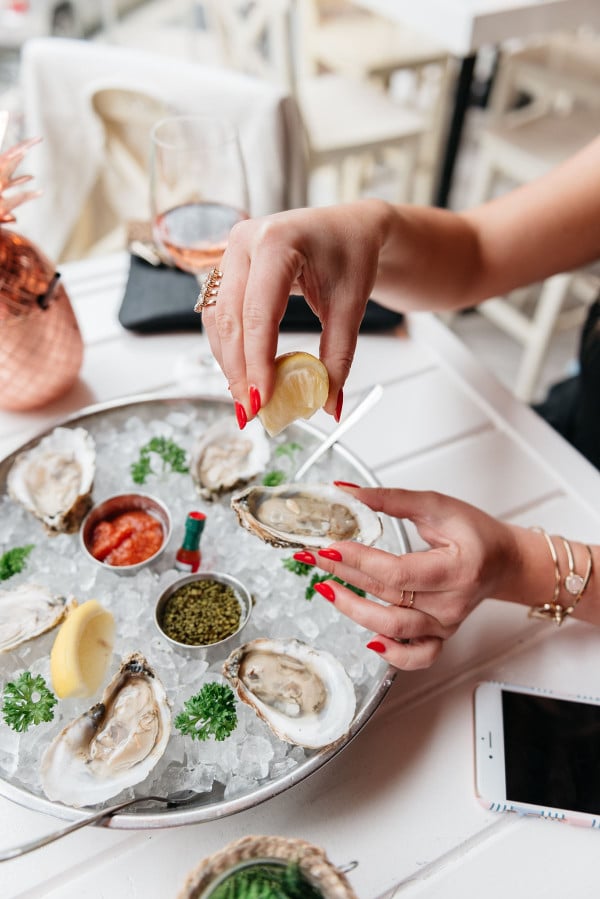 squeezing lemon on oysters rosé summer
