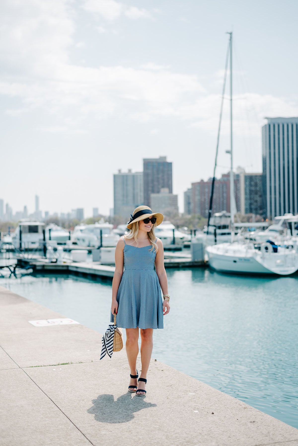 Bows & Sequins at Belmont Harbor in Chicago wearing a blue Old Navy gingham dress, a sun hat from Tuckernuck, Ralph Lauren navy wedges, a J.McLaughlin wicker tote, and a Kate Spade striped silk scarf.