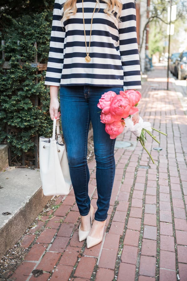 Bows & Sequins wearing a Tommy Hilfiger striped shirt, J Brand jeans, Kate Spade pumps, and a white bucket bag with a bouquet of pink peonies in Old Town Chicago. 