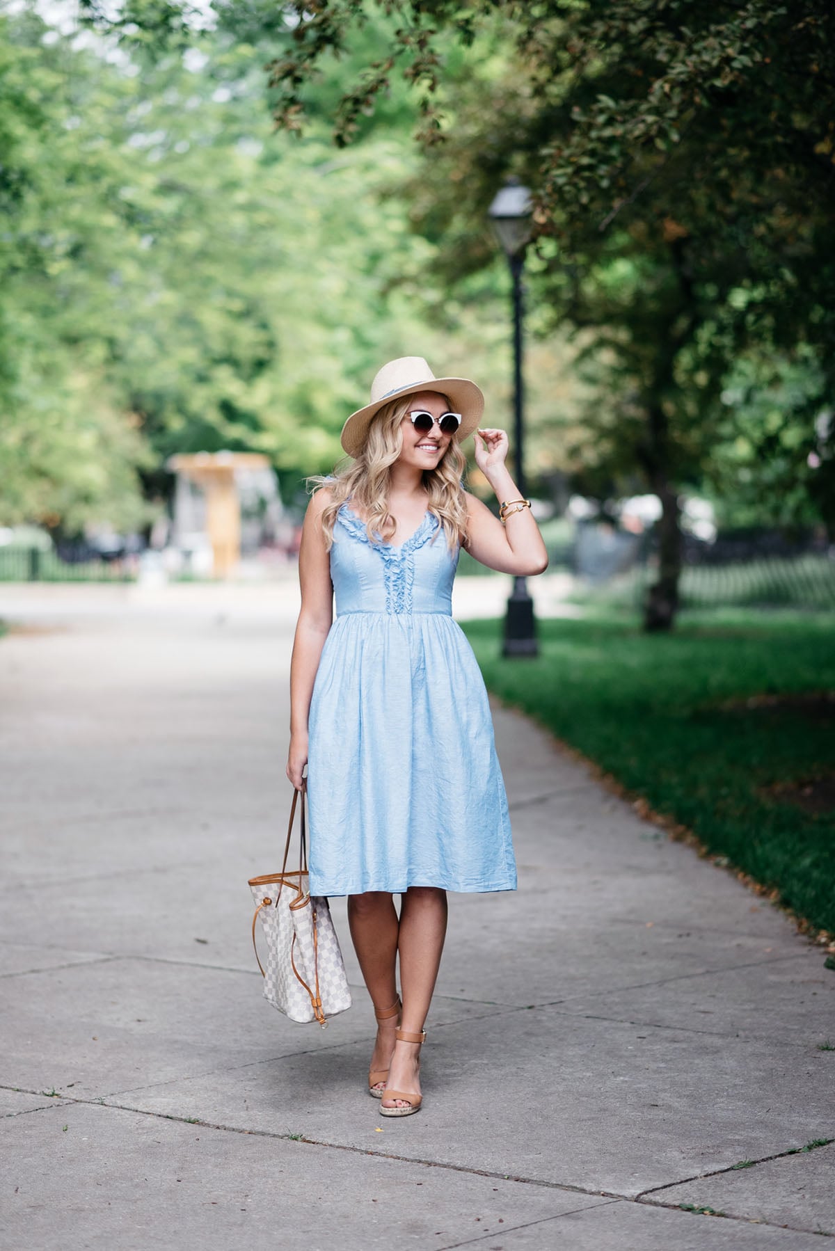 Bows & Sequins wearing a Banana Republic ruffled v-neck dress, Club Monaco straw hat, Louis Vuitton Damier Azur Neverfull Tote, Express cat-eye sunglasses, and Vince Camuto leather espadrille wedges to the Veuve Clicquot Polo Classic in New York.