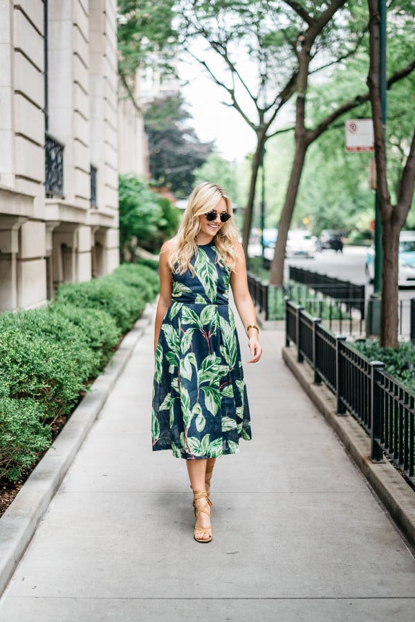 Blogger Jessica Sturdy (@bowsandsequins) wearing an Ann Taylor leaf print halter dress, Illesteva tortoise sunglasses, a J.McLaughlin wicker rattan handbag, and Ivanka Trump lace-up sandals in the Gold Coast in Chicago.