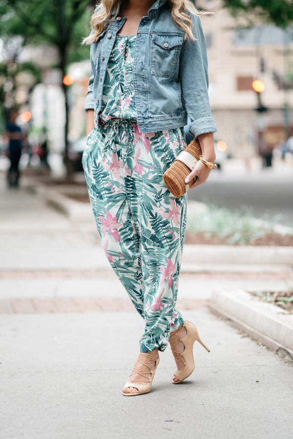 Bows & Sequins tackling the tricky trend of wearing a printed jumpsuit. She paired the leaf-printed, tropical jumpsuit with a denim jacket, lace-up heels, aviator sunglasses, and a rattan clutch.