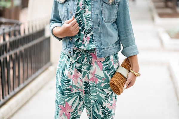 Bows & Sequins tackling the tricky trend of wearing a printed jumpsuit. She paired the pink and green leaf-printed, tropical jumpsuit with a denim jacket and a rattan clutch.