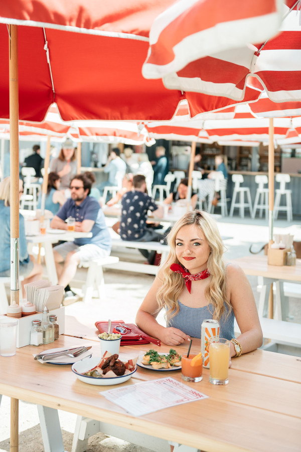 Bows & Sequins visits Parson's Chicken and Fish in Chicago. Jessica is wearing a white and blue gingham top with all red accessories: a red bandana tied around her neck, a red clutch, red sunglasses, and red lipstick. A fun Americana-inspired outfit that's perfect for Fourth of July festivities!