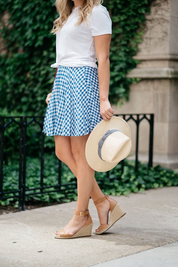Bows & Sequins wearing an Americana Red, White, and Blue outfit for July 4th weekend! A white Old Navy knotted tee, a blue and white J.Crew gingham skirt, a Club Monaco straw hat, a red Ralph Lauren handbag, and Vince Camuto leather espadrille wedges.