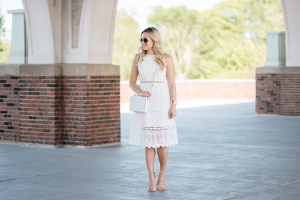Bows & Sequins wearing a white lace dress, white crossbody bag, and tan lace-up heels in Chicago.