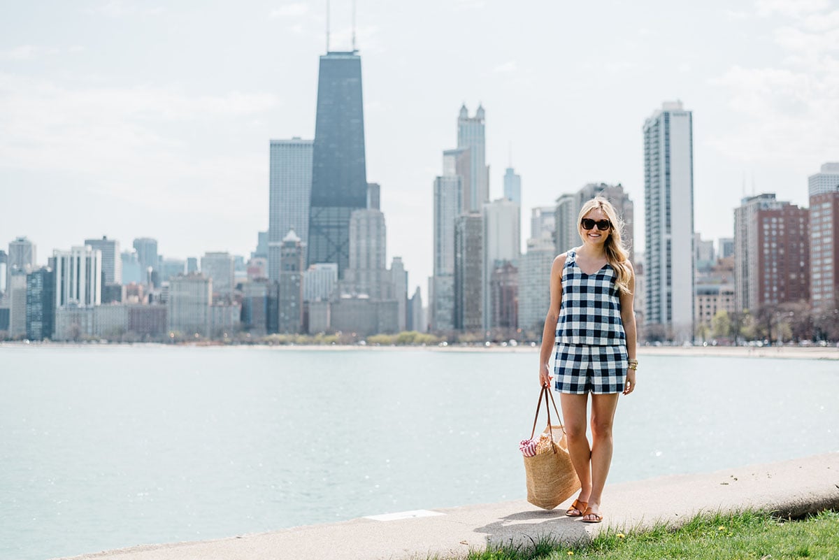 Bows & Sequins wearing a gingham short set having a picnic at North Avenue Beach with the Chicago Skyline in the background.