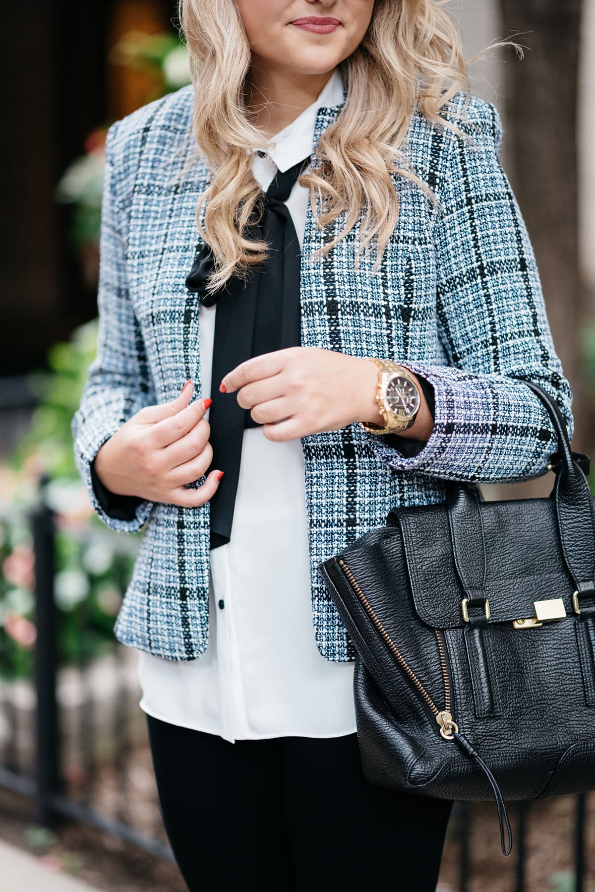 Bows & Sequins wearing a tweed jacket, a bow-tied blouse, black jeans, and a 3.1 Phillip Lim Pashli bag.