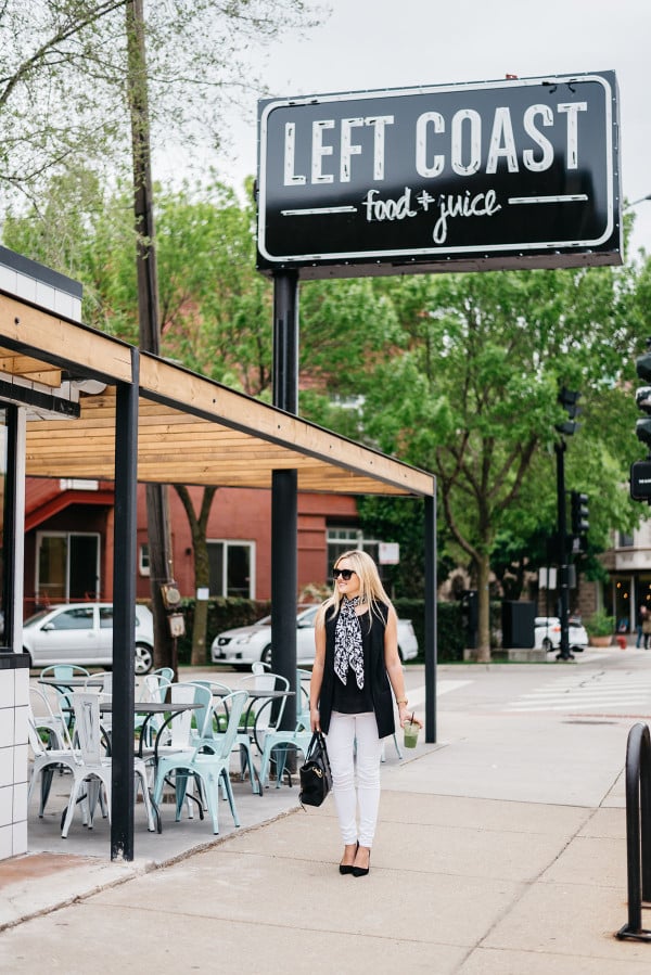 Bows & Sequins styles a casual summertime work outfit: white denim jeans, a silky blank tank top, a long black vest, a scarf tied at the neck, black pointed toe pumps, and a black tote!
