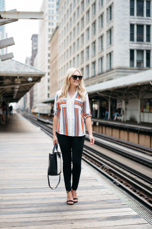 Chicago Blogger Jessica Sturdy of Bows & Sequins styling a striped button-front shirt, black skinny jeans, ankle-strap heels, and a color-blocked black and white tote for a work-appropriate outfit on the Chicago El Train platform in the Loop downtown.