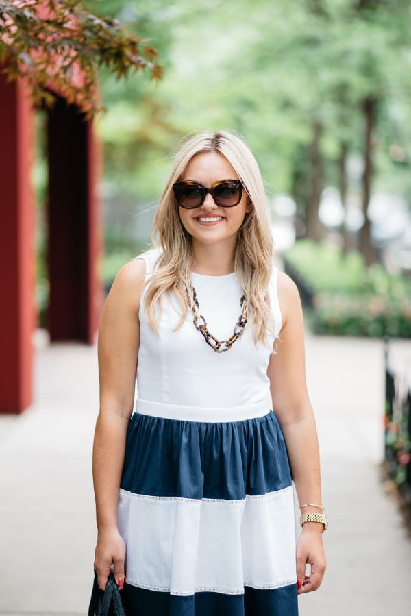 Blogger @bowsandsequins wearing a navy and white striped Elizabeth McKay dress with Celine sunglasses, a navy blue Kate Spade bag, and a tortoise link necklace.