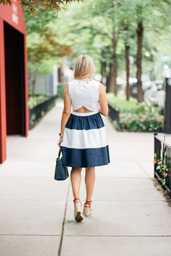 Chicago fashion blogger Jessica Sturdy of @bowsandsequins wearing a navy blue and white striped dress with a cutaway back detail. She paired it with a navy handbag and leather espadrille wedges.
