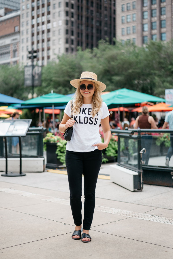 Chicago Blogger Jessica Sturdy of Bows & Sequins styling an Express t-shirt and black skinny jeans with black criss-cross leather slides, a Janessa Leone straw hat, a black and gold Gucci bag, and big round sunglasses in Millennium Park.