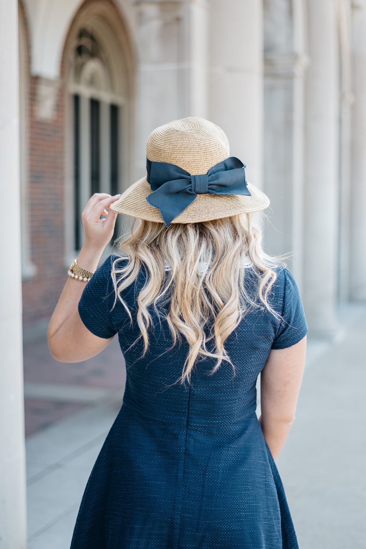 Bows & Sequins styling a navy fit and flare dress with a straw hat with a navy grosgrain bow!