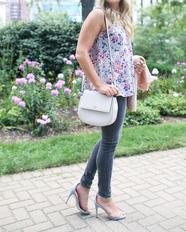 Fashion blogger Bows & Sequins wearing grey jeans, a floral paisley-printed top from Old Navy, a Kate Spade crossbody bag, and Dior sunglasses.