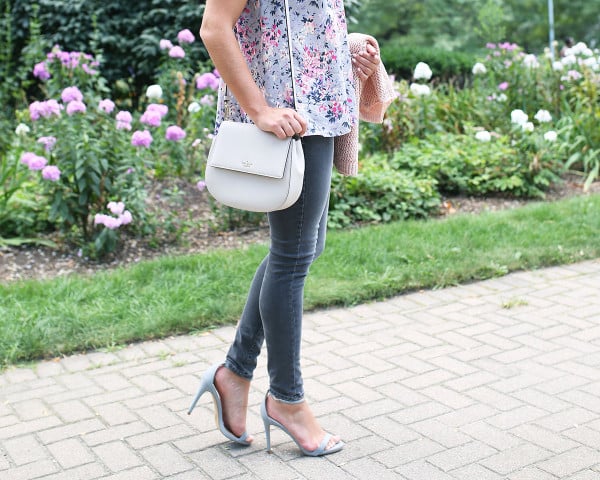 Fashion blogger Bows & Sequins wearing grey jeans, a floral paisley-printed top from Old Navy, a Kate Spade crossbody bag, and Dior sunglasses.