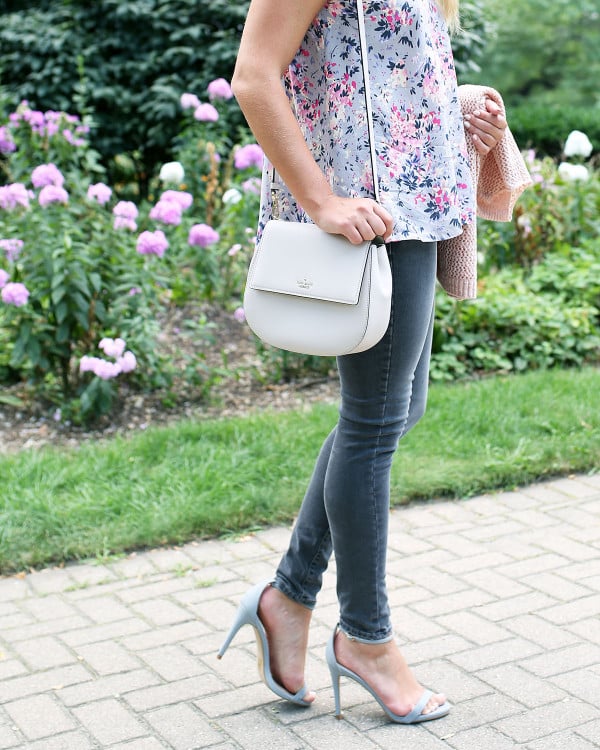 Fashion blogger Bows & Sequins wearing grey jeans, a floral paisley-printed top from Old Navy, a Kate Spade crossbody bag, and Dior sunglasses.