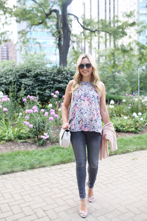 Fashion blogger Bows & Sequins wearing grey jeans, a floral paisley-printed top from Old Navy, a Kate Spade crossbody bag, and Dior sunglasses.