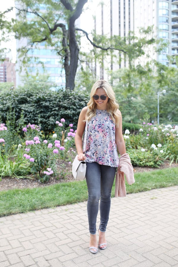 Fashion blogger Bows & Sequins wearing grey jeans, a floral paisley-printed top from Old Navy, a Kate Spade crossbody bag, and Dior sunglasses.
