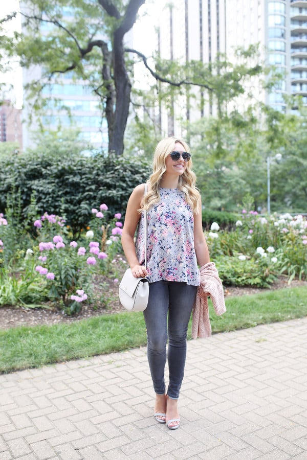 Fashion blogger Bows & Sequins wearing grey jeans, a floral paisley-printed top from Old Navy, a Kate Spade crossbody bag, and Dior sunglasses.