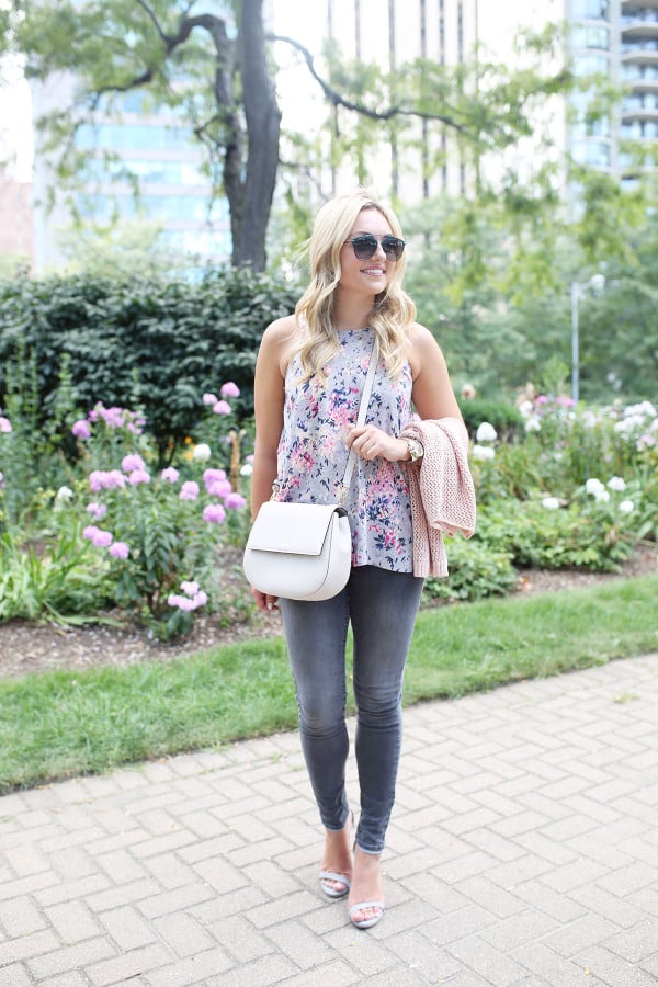 Fashion blogger Bows & Sequins wearing grey jeans, a floral paisley-printed top from Old Navy, a Kate Spade crossbody bag, and Dior sunglasses.