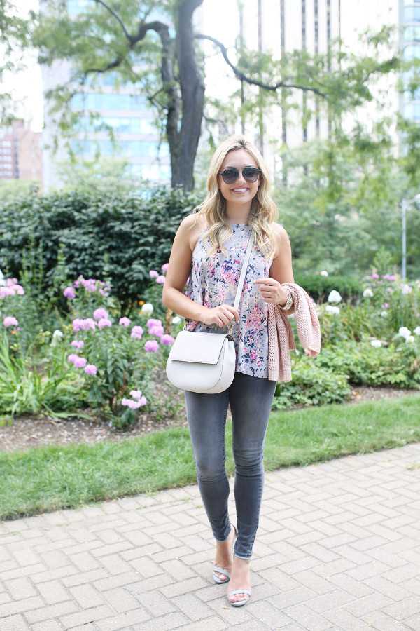 Fashion blogger Bows & Sequins wearing grey jeans, a floral paisley-printed top from Old Navy, a Kate Spade crossbody bag, and Dior sunglasses.