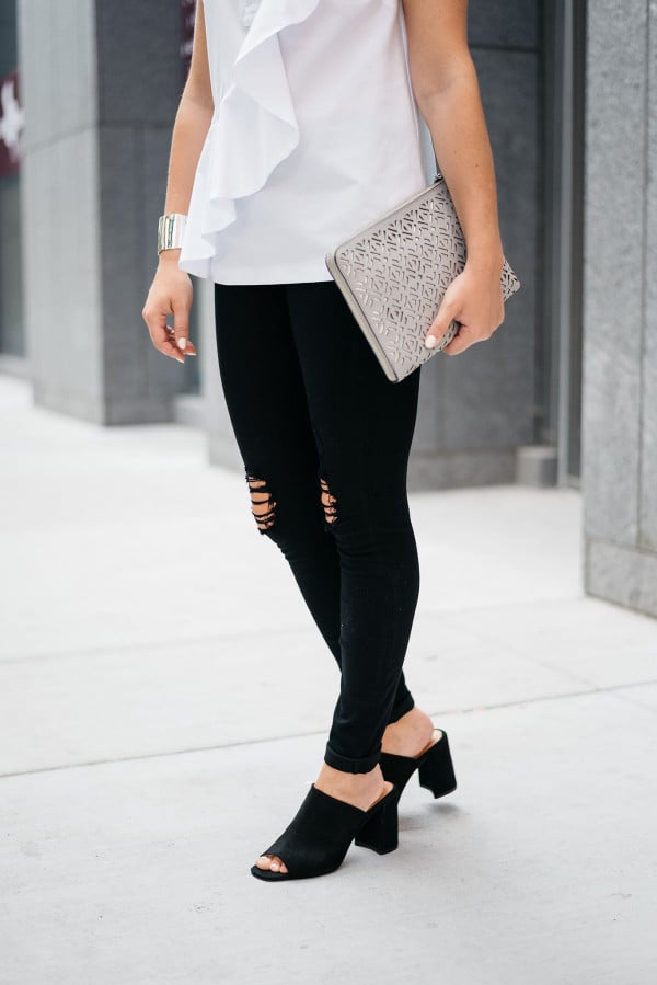 Bows & Sequins wearing a white ruffled top, black destroyed denim, and black suede mules.