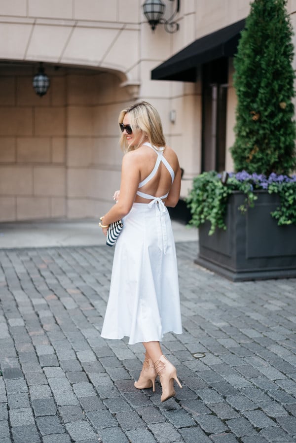 Bows & Sequins wearing a crisscross white dress, sunglasses, and heels in Chicago.