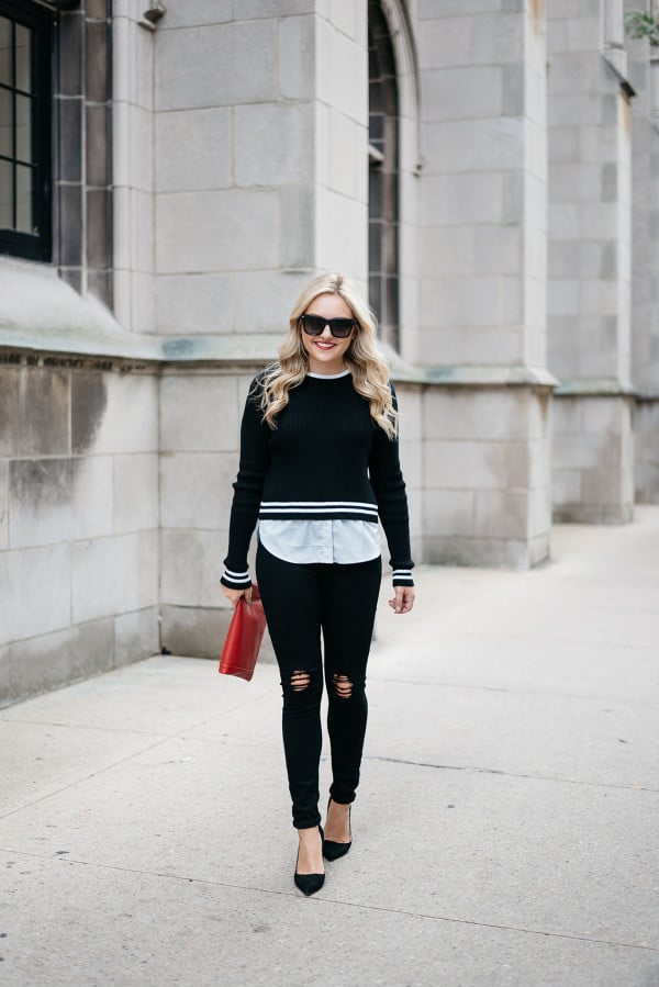 Jessica Sturdy of Bows & Sequins, a fashion-focused lifestyle blog, wearing a black and white stripe sweater, white shirt, black ripped jeans, black heels, and a red purse.