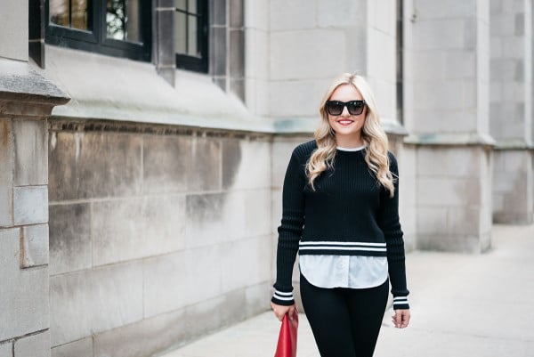 Jessica Sturdy of Bows & Sequins, a fashion-focused lifestyle and travel blog, wearing a black and white stripe sweater, white shirt, black jeans, and red clutch purse.