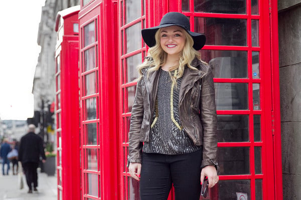 Travel and fashion blogger Jessica Sturdy of Bows & Sequins wearing a black hat, moto jacket, beaded tank, and black pants in London.