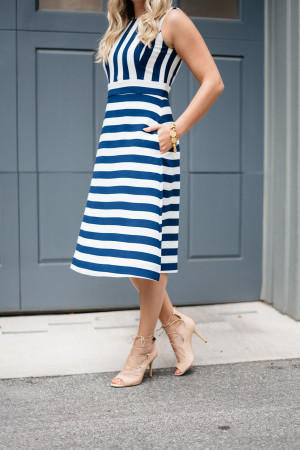 Fashion blogger Jessica Sturdy of Bows & Sequins styling a navy and white stripe dress, nude pumps, and gold bracelet.