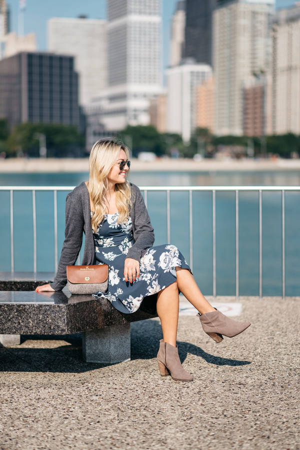 Fashion blogger Bows & Sequins styles a blue navy floral dress, long grey sweater, aviator sunglasses, Sword & Plough clutch purse, and Steve Madden booties in Chicago.