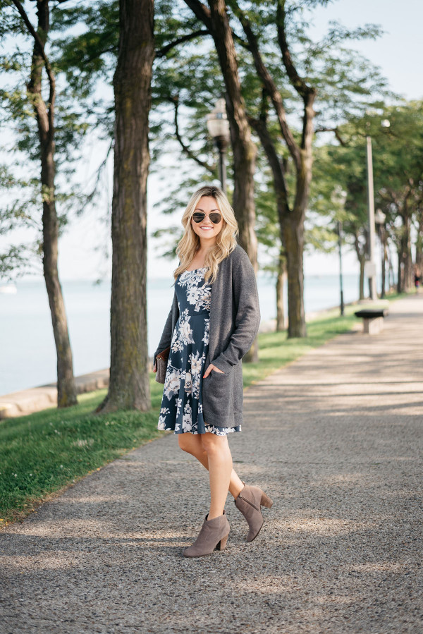 Fashion blogger Bows & Sequins styles a blue navy floral dress, Old Navy long grey sweater, aviator sunglasses, clutch purse, and Steve Madden booties.