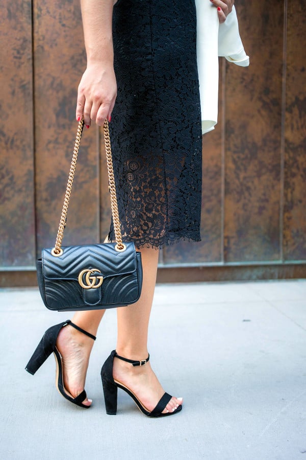 Bows & Sequins, a fashion-focused lifestyle blog, holds a black Gucci purse, black dress, and black heels in New York.