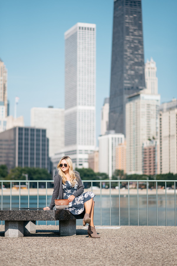 Bows & Sequins, fashion-focused lifestyle blogger, wears a navy floral dress, grey sweater, and tan and grey clutch in Chicago.