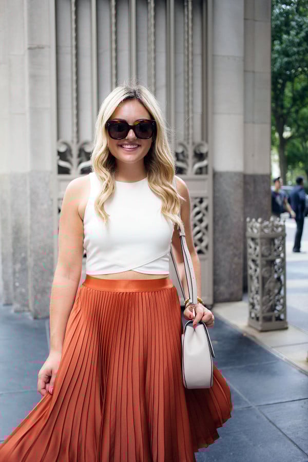 Blogger Bows & Sequins styling a crop top in a sophisticated way. She paired it with a pleated skirt, Celine sunglasses, and a Kate Spade crossbody saddle bag. 
