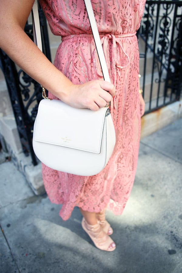 Blogger Bows & Sequins styling a Wayf pink lace midi dress, a Kate Spade Byrdie crossbody bag, and Vince Camuto nude lace-up heels during NYFW.