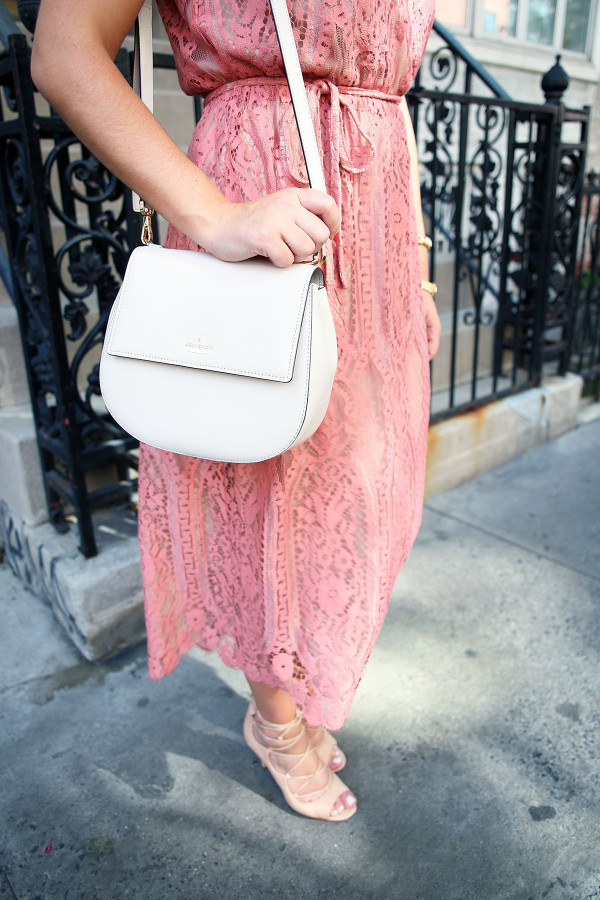 Blogger Bows & Sequins styling a Wayf pink lace midi dress, a Kate Spade Byrdie crossbody bag, and Vince Camuto nude lace-up heels during NYFW.