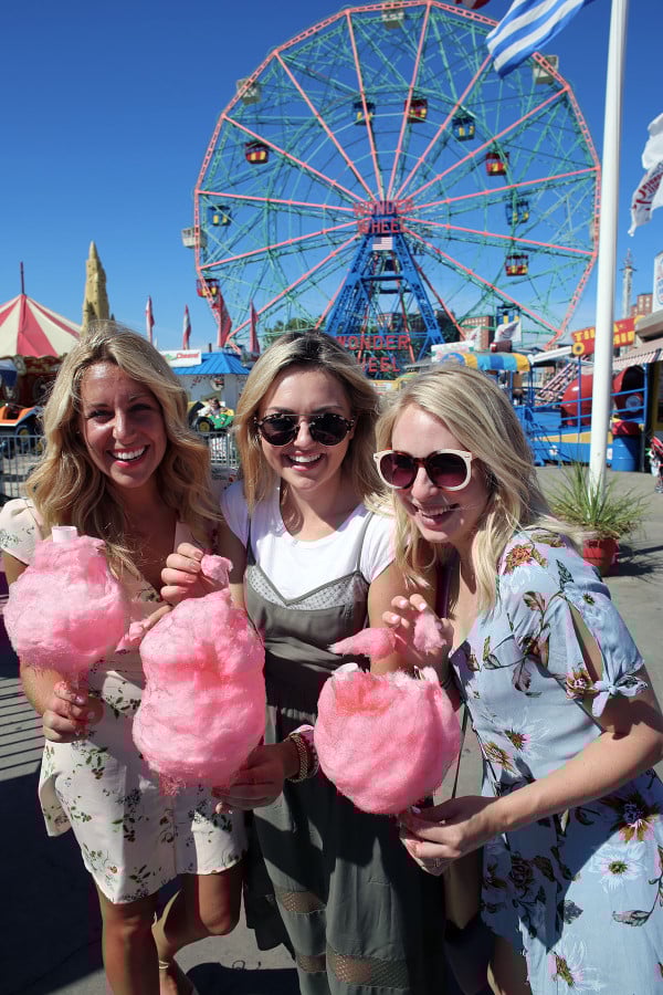 Bloggers Lauren Wells Jessica Sturdy Cambria Grace with cotton candy in front of the ferris wheel at Coney Island in NYC