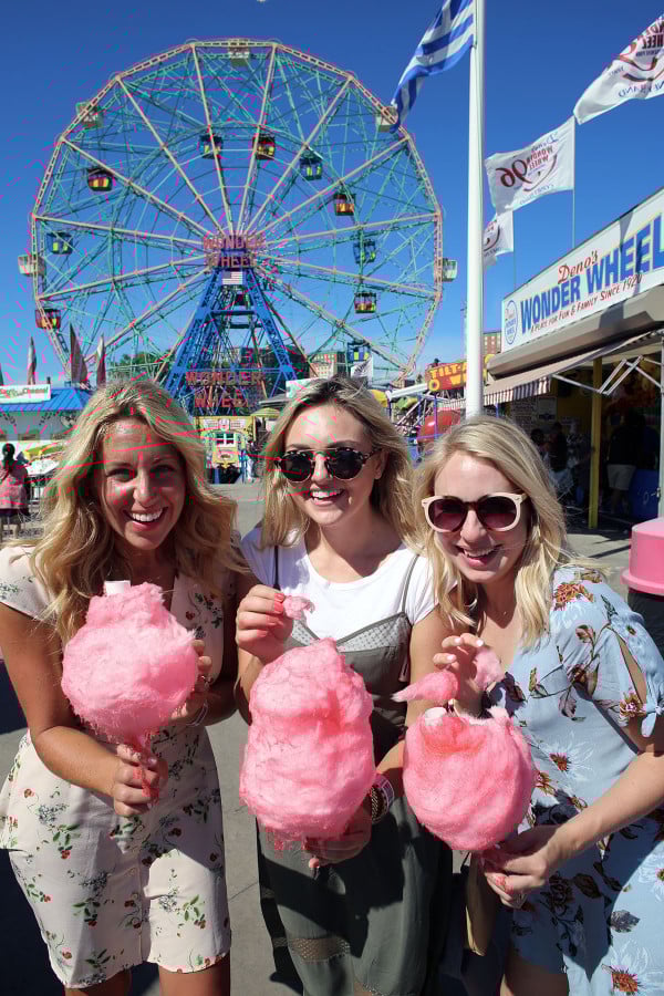 Bloggers Lauren Wells Jessica Sturdy Cambria Grace with cotton candy in front of the ferris wheel at Coney Island in NYC