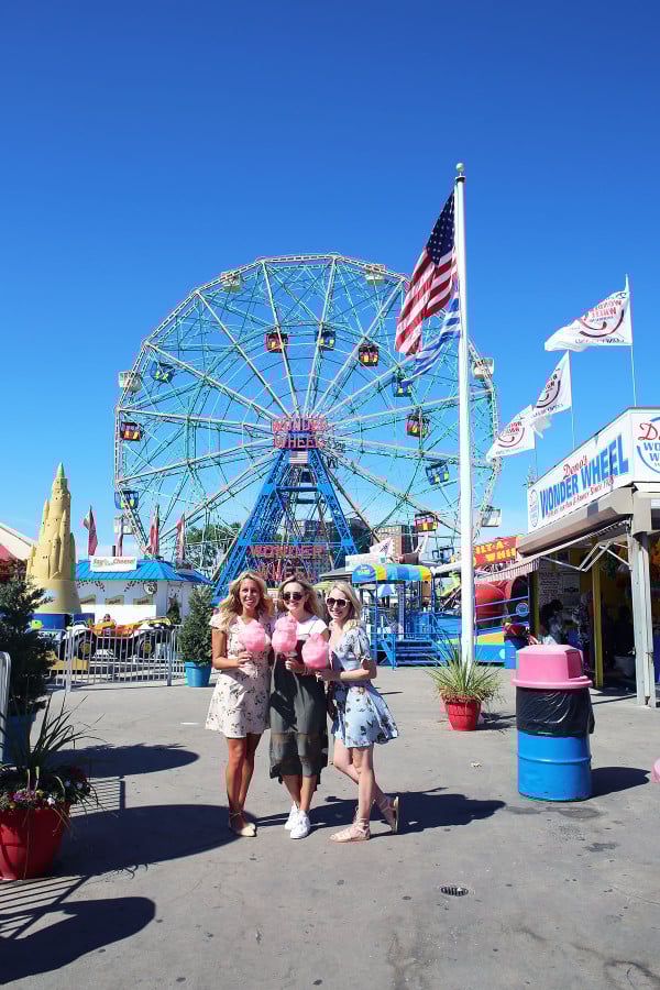 Bloggers Lauren Wells Jessica Sturdy Cambria Grace with cotton candy in front of the ferris wheel at Coney Island in NYC