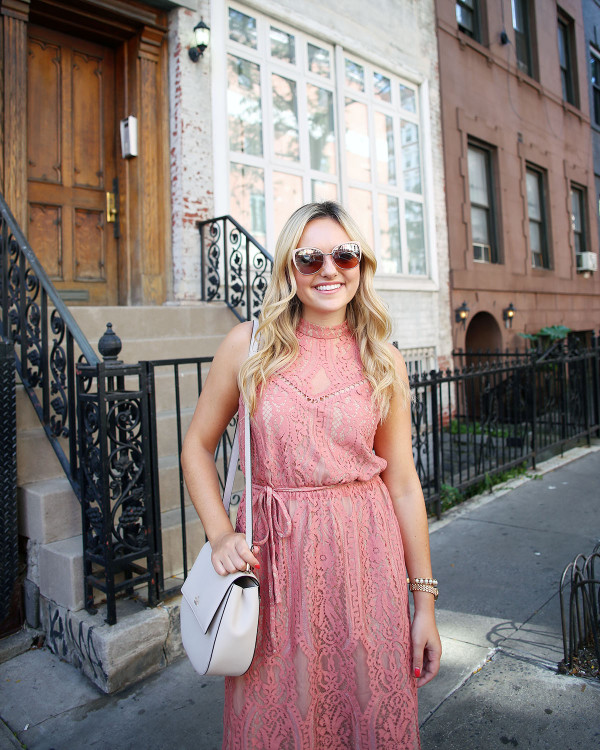 Fashion blogger Bows & Sequins wearing a pink lace midi dress during New York Fashion Week. Jessica styled the outfit with nude lace-up sandals, a Kate Spade crossbody bag, and blush pink square cat-eye sunglasses. Makeup was done by Mary Kay via GlamSquad!