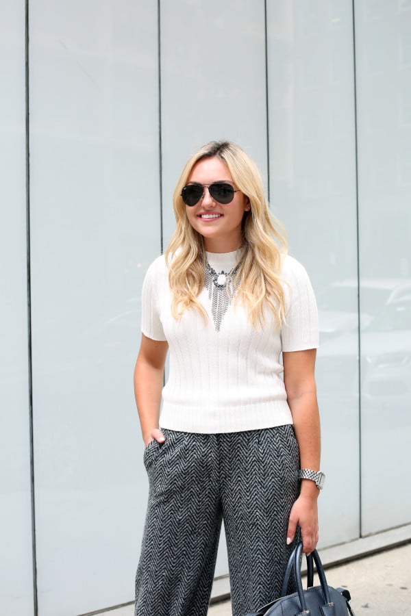 Bows & Sequins styling a monochromatic fall work outfit with a short sleeve sweater, statement necklace, and wool pants.